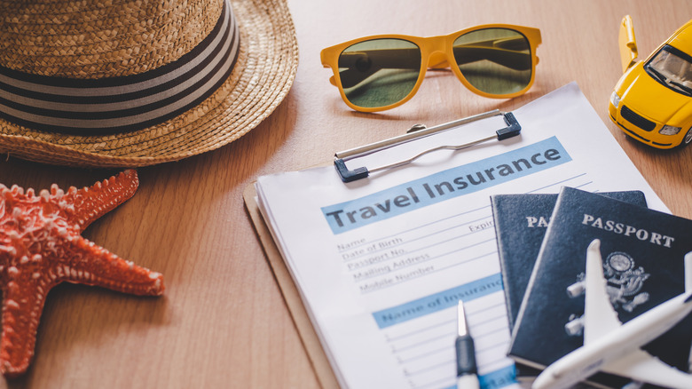 A travel insurance form next to travel related items
