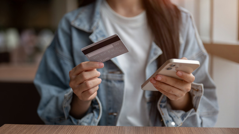 Women holding phone and credit card.