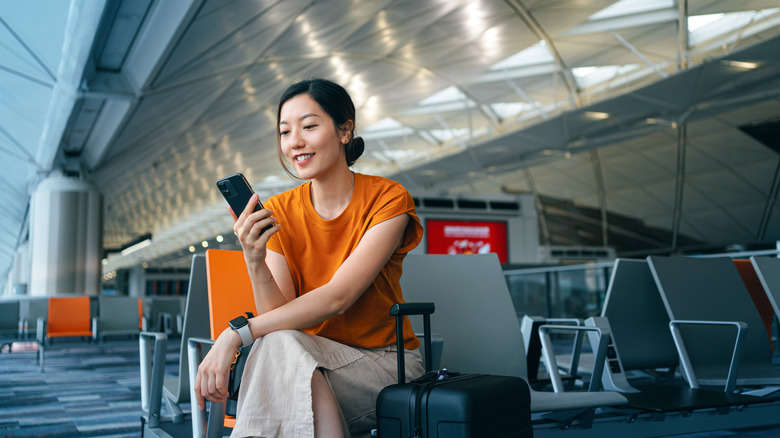 A woman using a smartphone while waiting for the departure in the airport
