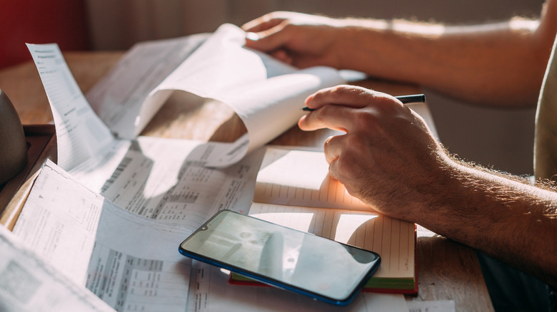 Person with calculator going over utility bill documents