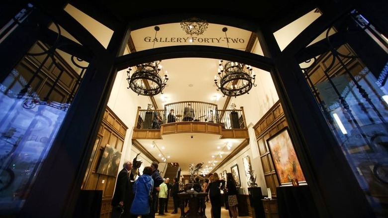 An evening gathering of people inside Gallery Forty-Two taken from outside.