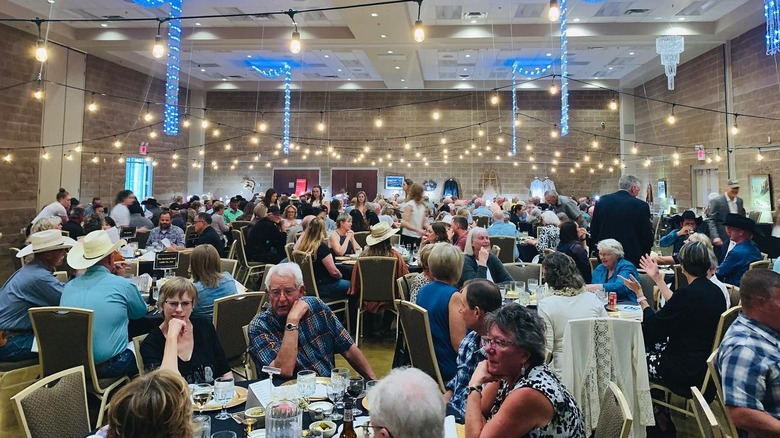 A large gathering of seated guests having dinner in a banquet hall.