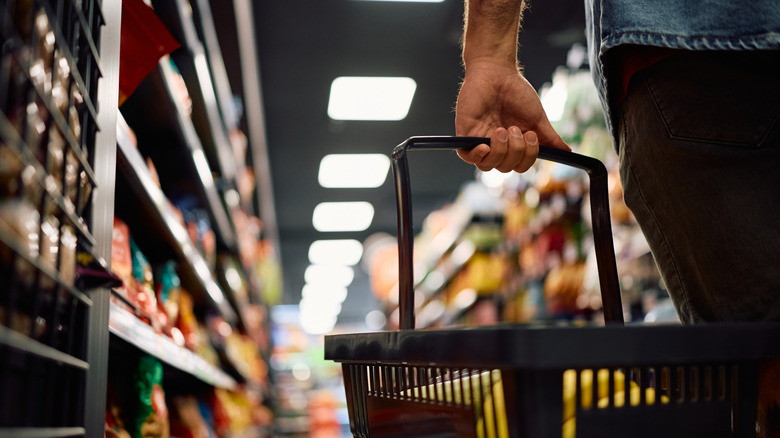 Person holding handheld cart at grocery store