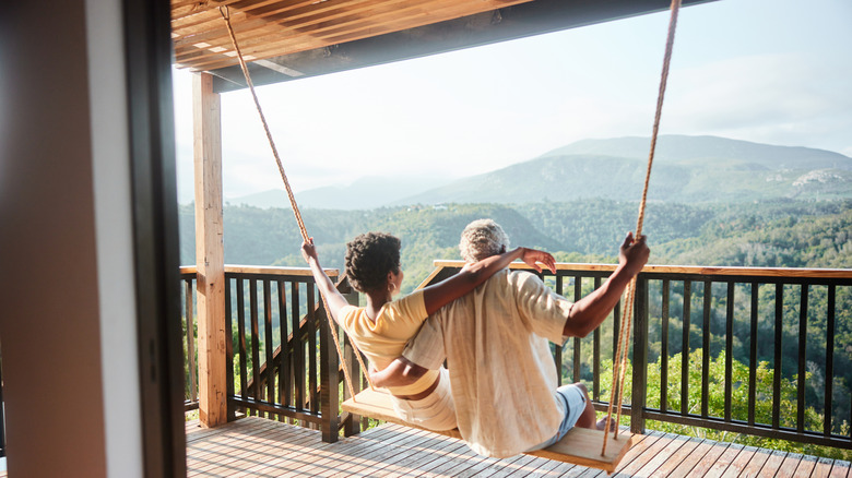 Couple on a porch swing overlooking nature.