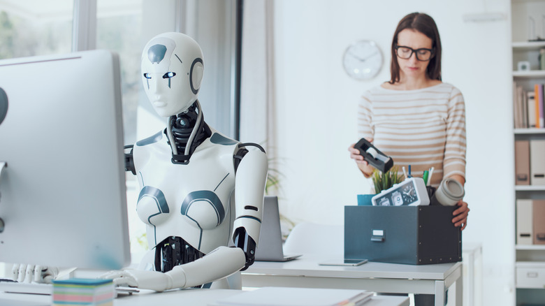 A recently fired woman packing her things as a robot does her job