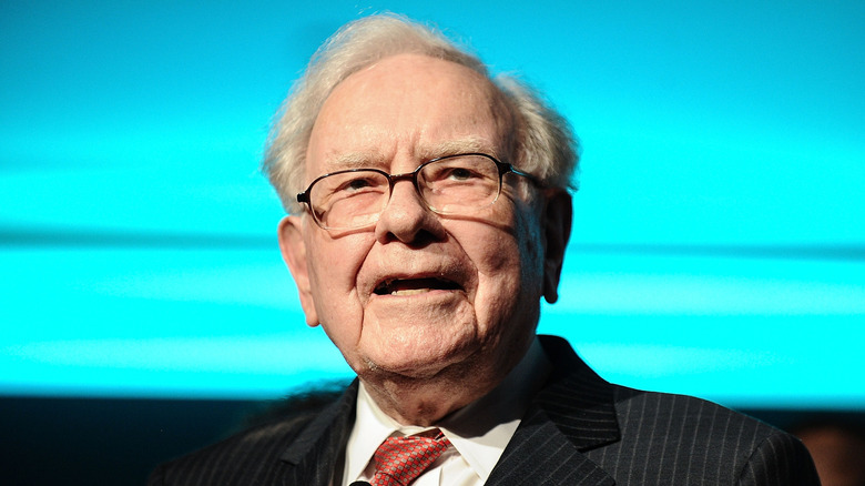 Warren Buffett speaking in front of blue background