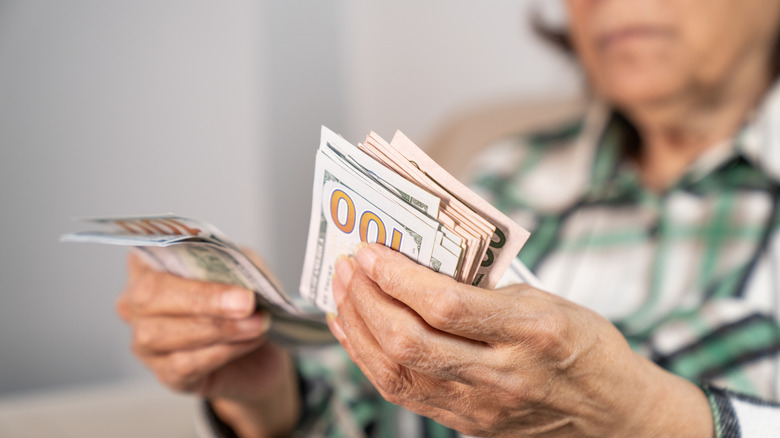 senior holding a pile of cash