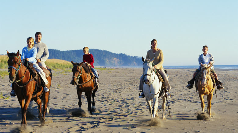 family riding horseback on a beach