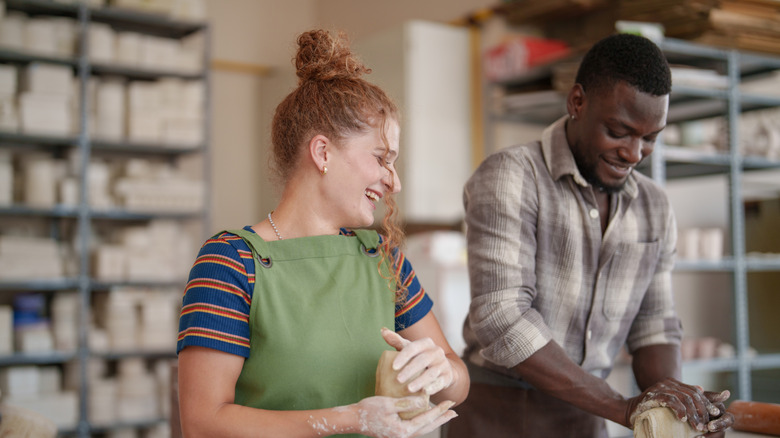 couple forming clay in pottery studio