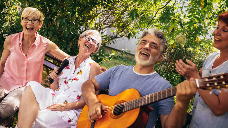 several older friends sing in park as guitarist plays