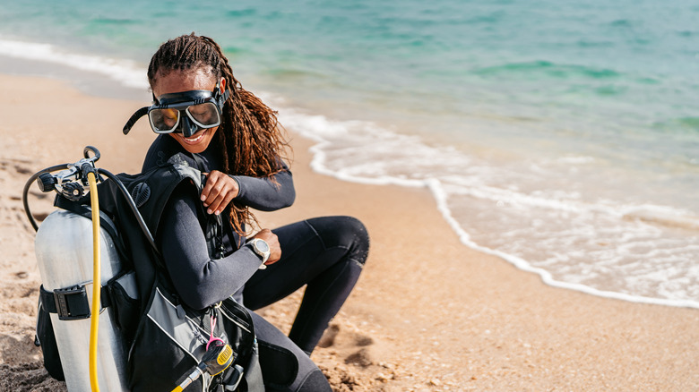 woman on beach in scuba gear securing tank