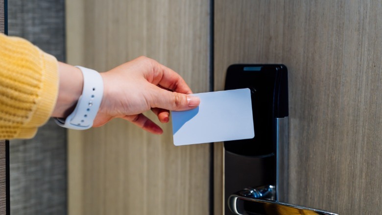 A person opening up a modern hotel room door with a key card.