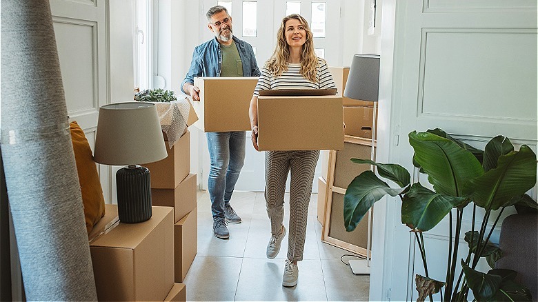 Couple carrying boxes into house