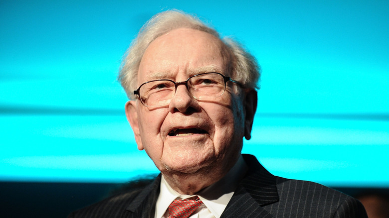 Warren Buffett speaking in front of a blue background