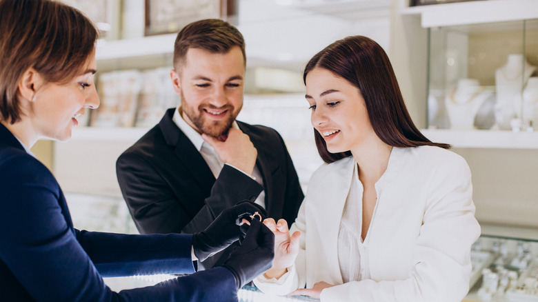Jeweler shows off engagement ring as couple smiles