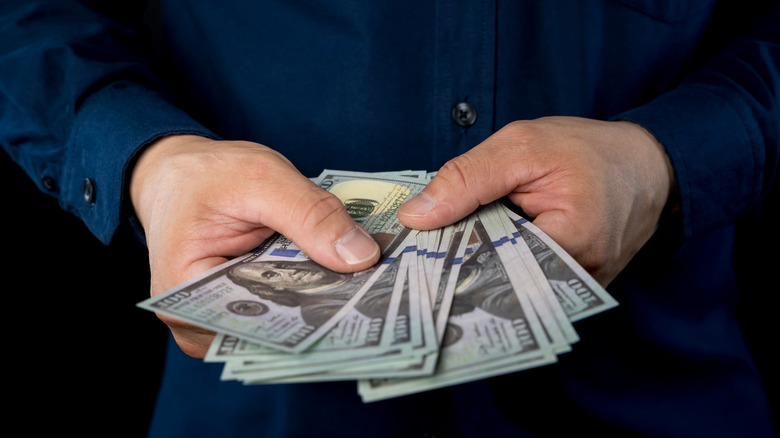 Closeup of a man's hands holding $100 bills