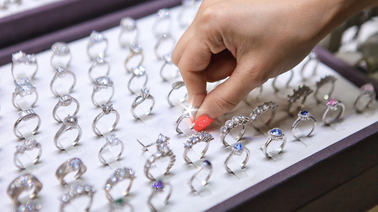 A woman's hand with painted nails picking a glistening ring from a box