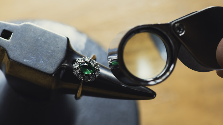 Closeup of luxury emerald ring being examined using a magnifying glass