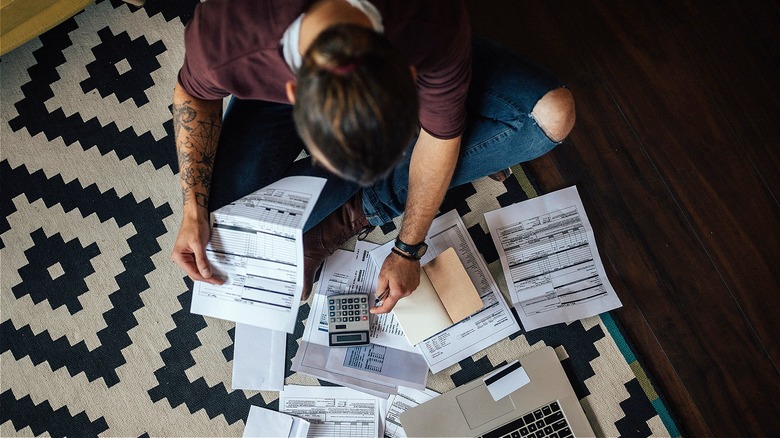 Person on floor, calculating bills