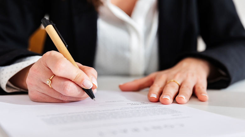Close up view of young businesswoman hands signing a contract in the office.