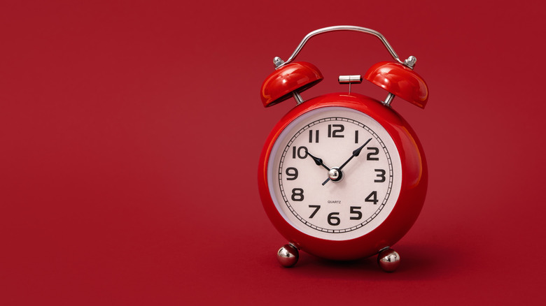 Red alarm clock on red background.
