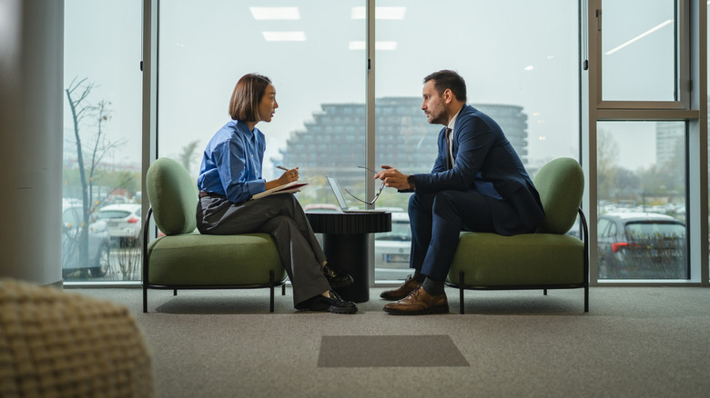 Two professionals in a modern office engaged in a serious interview.