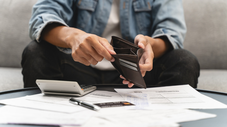 Young man opening empty wallet stress to find money to pay for life insurance coverage.
