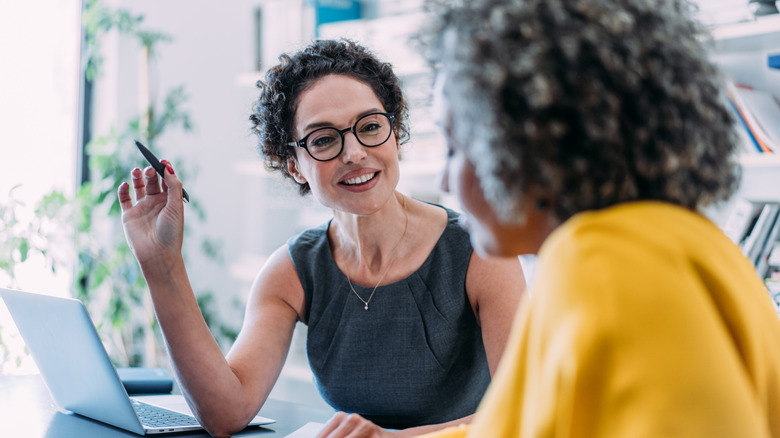Two professional women talking on a desk