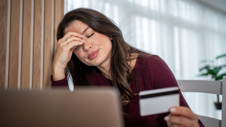 woman with hand on her head looking at credit card