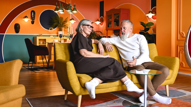 Senior couple relax on vintage chair surrounded by similarly vintage furniture