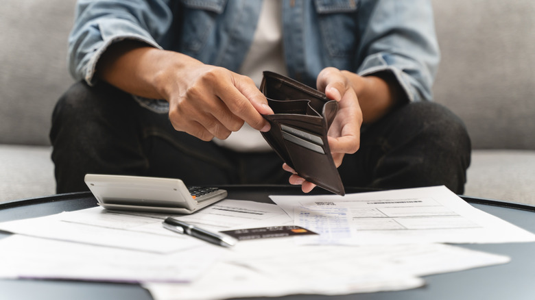 Person sitting on sofa with bills spread out on table.