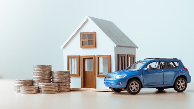 Stacks of coins next to toy house and toy car