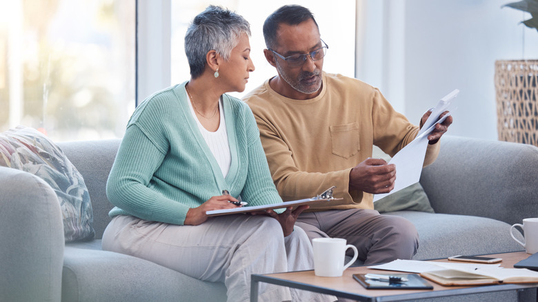 an older couple reviewing financial documents on a gray couch