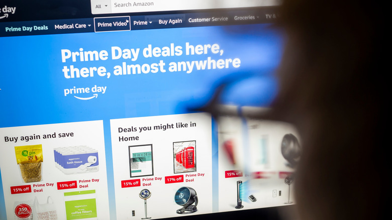 A blurred computer user in the right of frame checks out Prime Deal Days on a computer screen