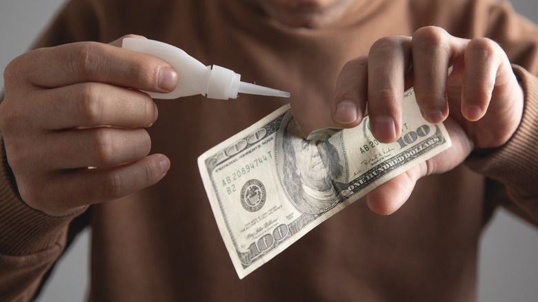 Person trying to glue a torn $100 bill