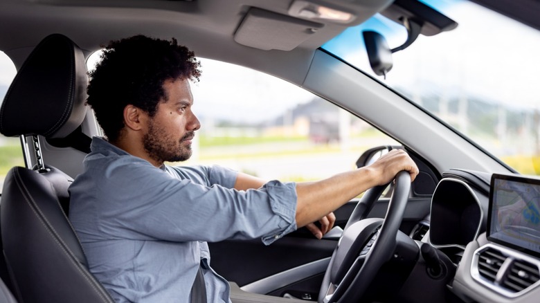 A man looking focused while driving a car.