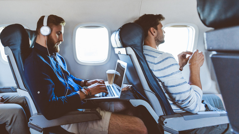 Two young men sitting in coach on an airplane