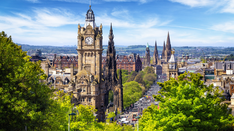 Near aerial shot of Scottish city with trees in the front and a busy street below