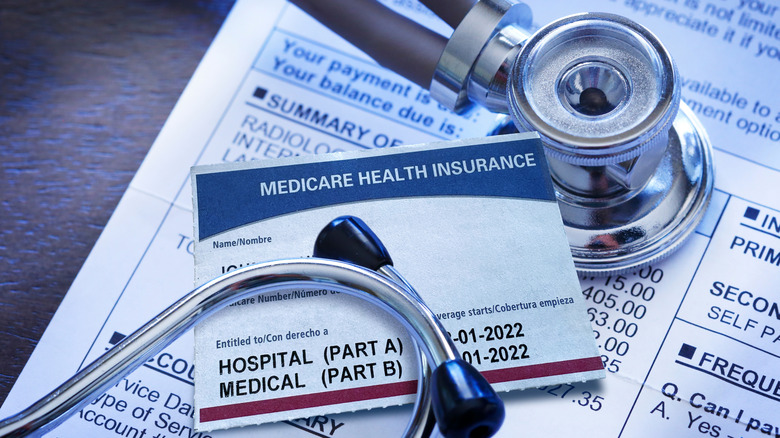 A stethoscope and Medicare insurance card sits on top of a medical bill document