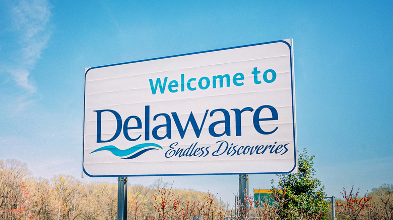 The "Welcome to Delaware" sign closeup against a blue sky.