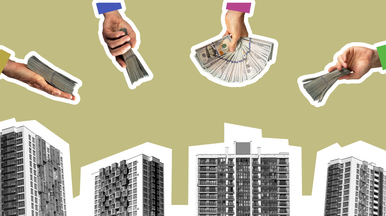 hands holding money over apartment buildings