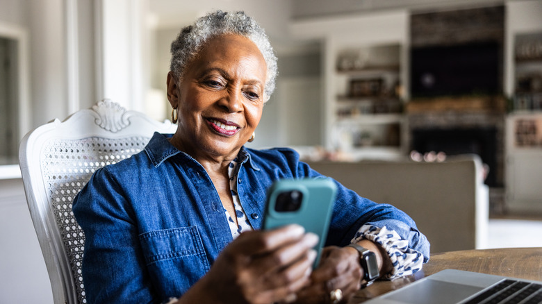 Senior woman using smartphone at kitchen table