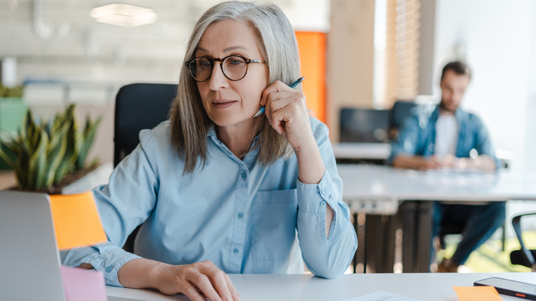 A mature woman sitting at a work desk.