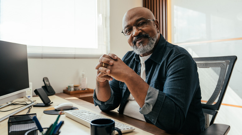 A mature man sitting at a work desk.