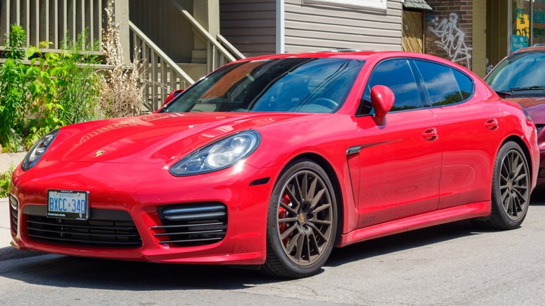 Red Porsche Panamera parked on the street next to a house