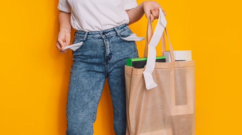 woman holding shopping bags and pulling out her pocket to show there's no money in it