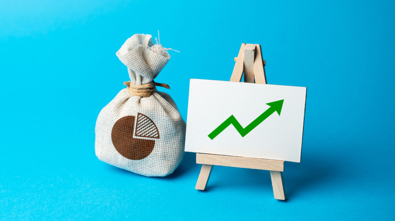 upward arrow on whiteboard next to a bag of money