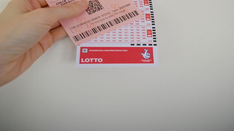 hand holding lottery ticket and play slip