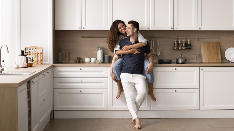 A couple smiling in their elegant but simple kitchen