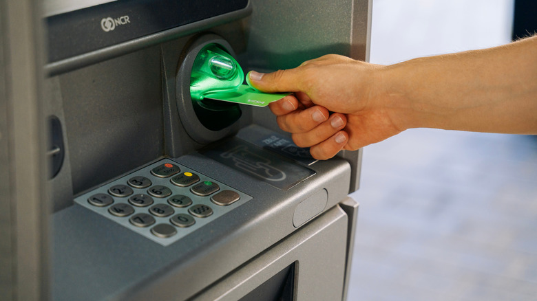 A man inserting a debit card into an ATM